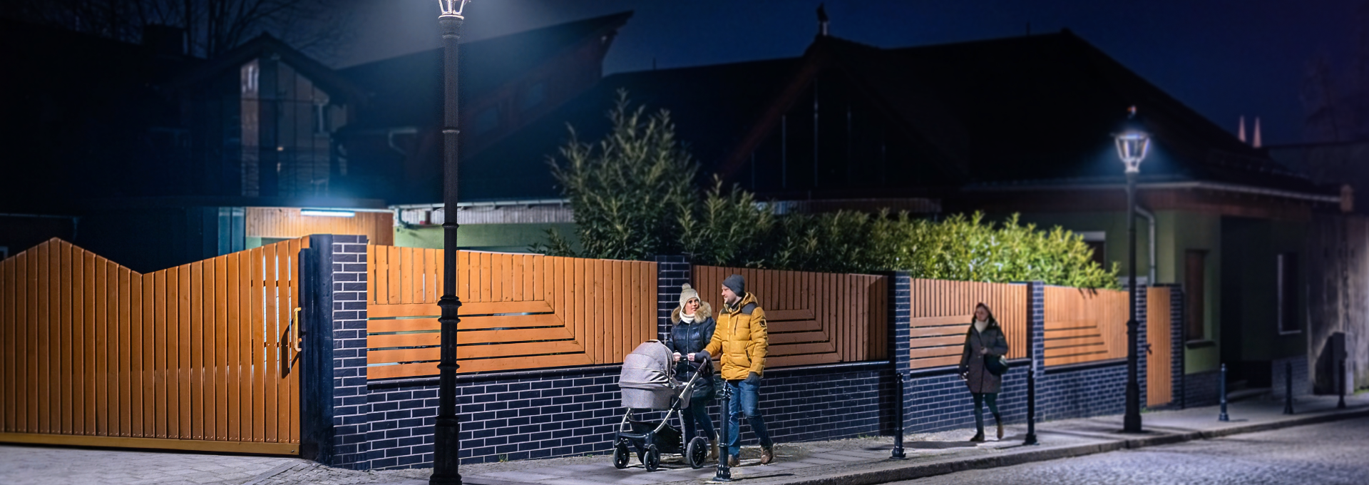 Ludzie spacerujący nocą dobrze oświetloną ulicą.